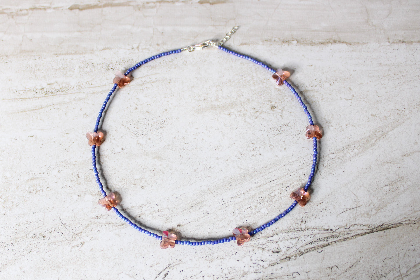 A bold and playful blue and orange butterfly necklace featuring vibrant glass beads and a whimsical butterfly charm.