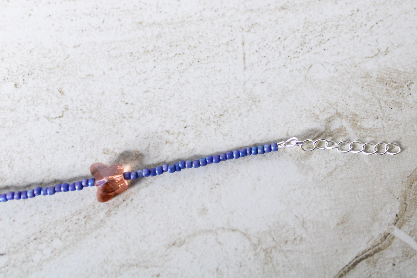 Close-up of the 1-inch extender chain on the blue and orange butterfly necklace, emphasizing its adjustable design.