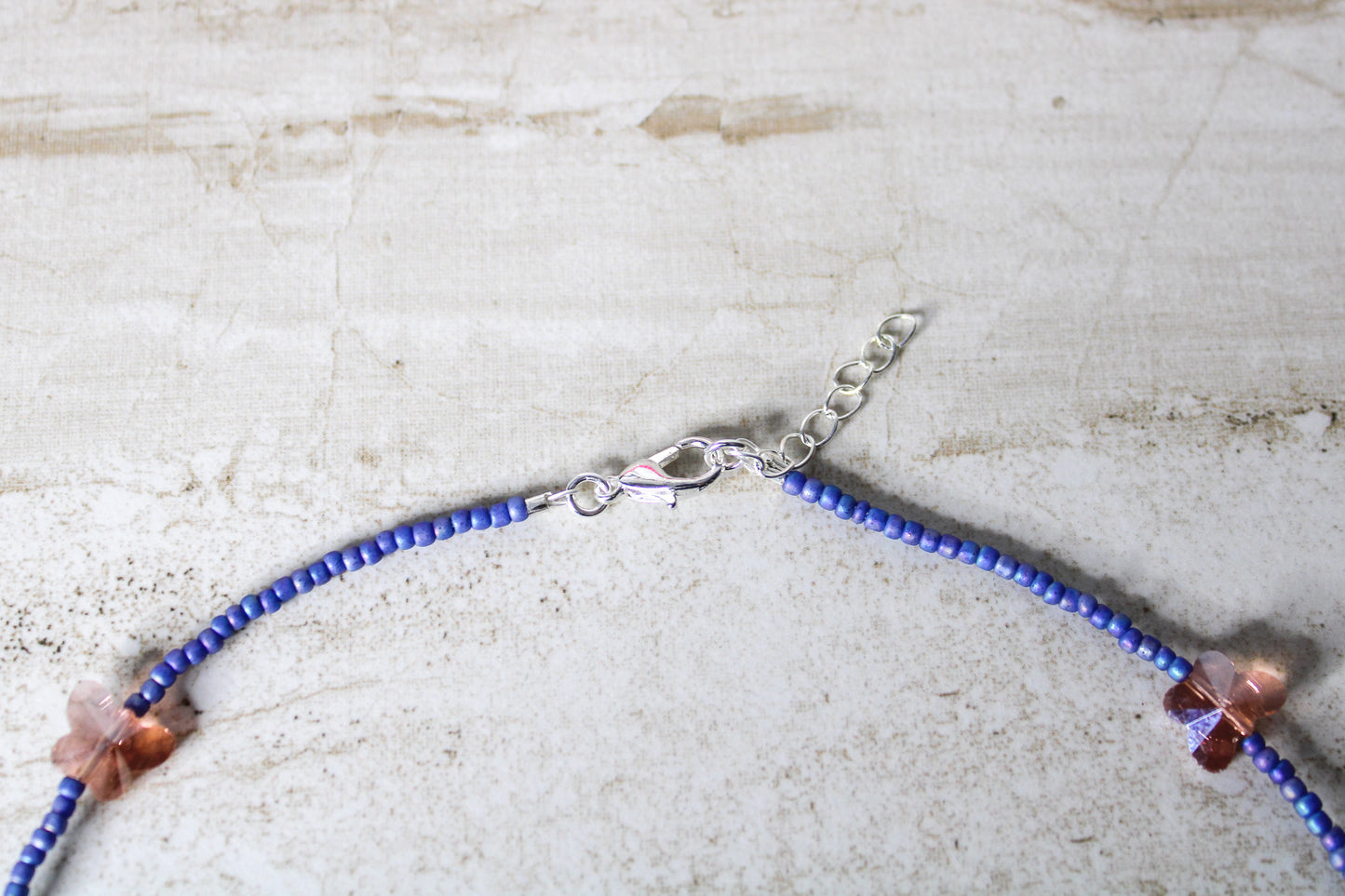 A bold and playful blue and orange butterfly necklace featuring vibrant glass beads and a whimsical butterfly charm.