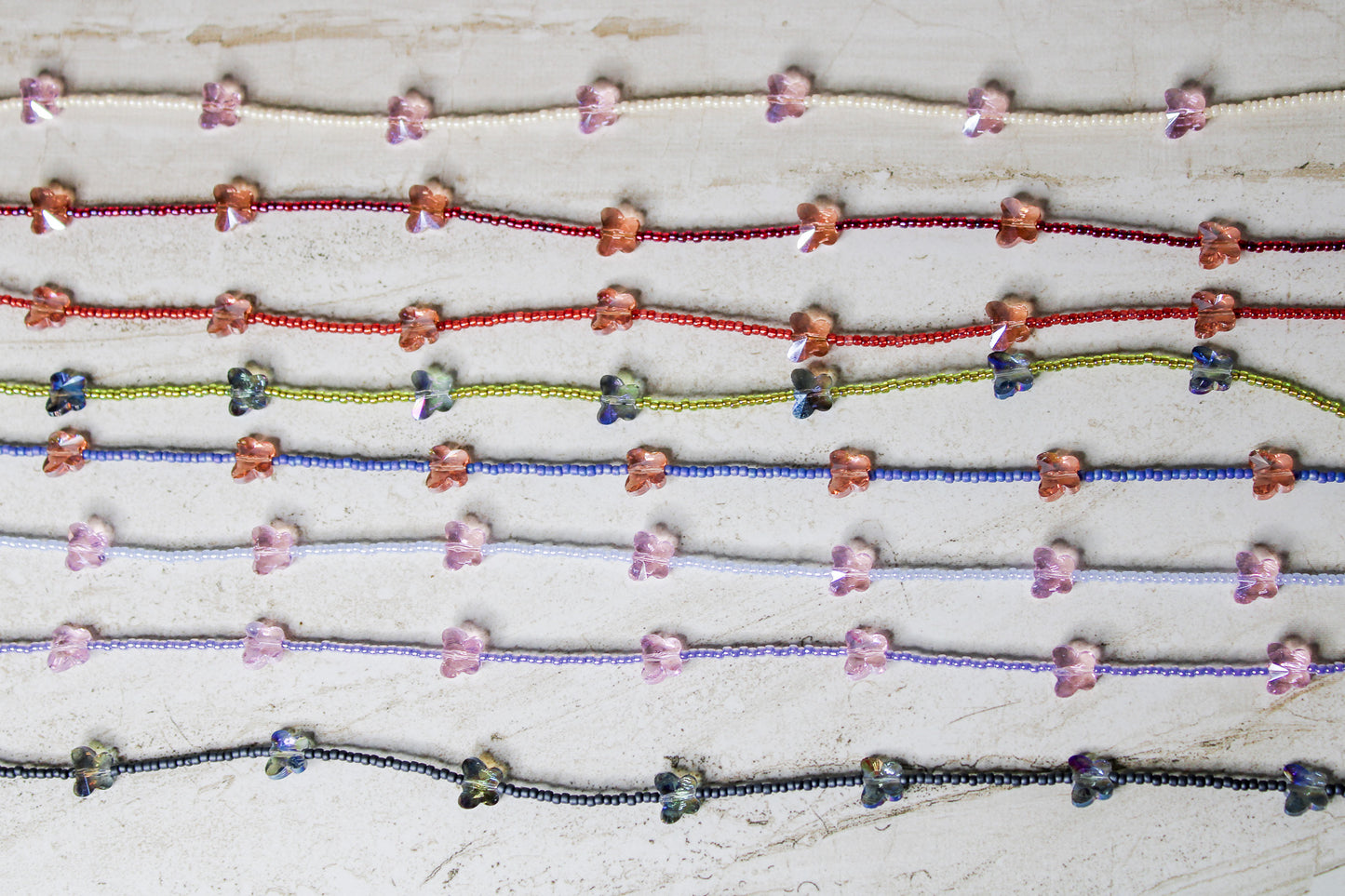 8 crystal butterfly necklaces featuring different color combinations.