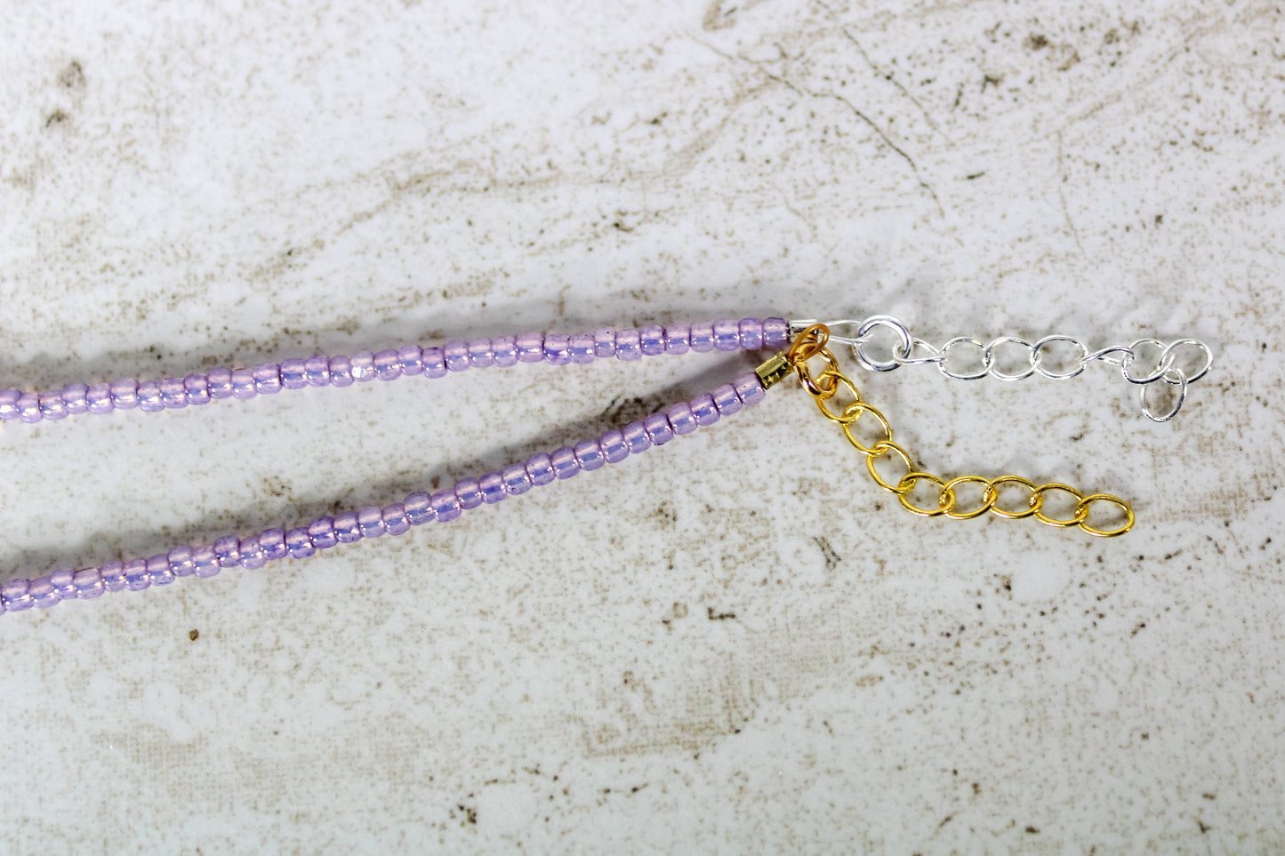 A close up of the gold and silver extender chains on a purple bracelet.