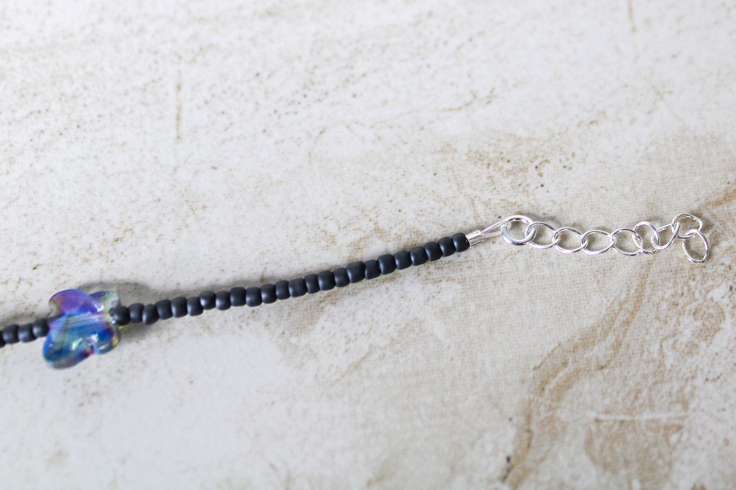 Close-up of the 1-inch extender chain on the grey and blue butterfly necklace, emphasizing its adjustable feature.