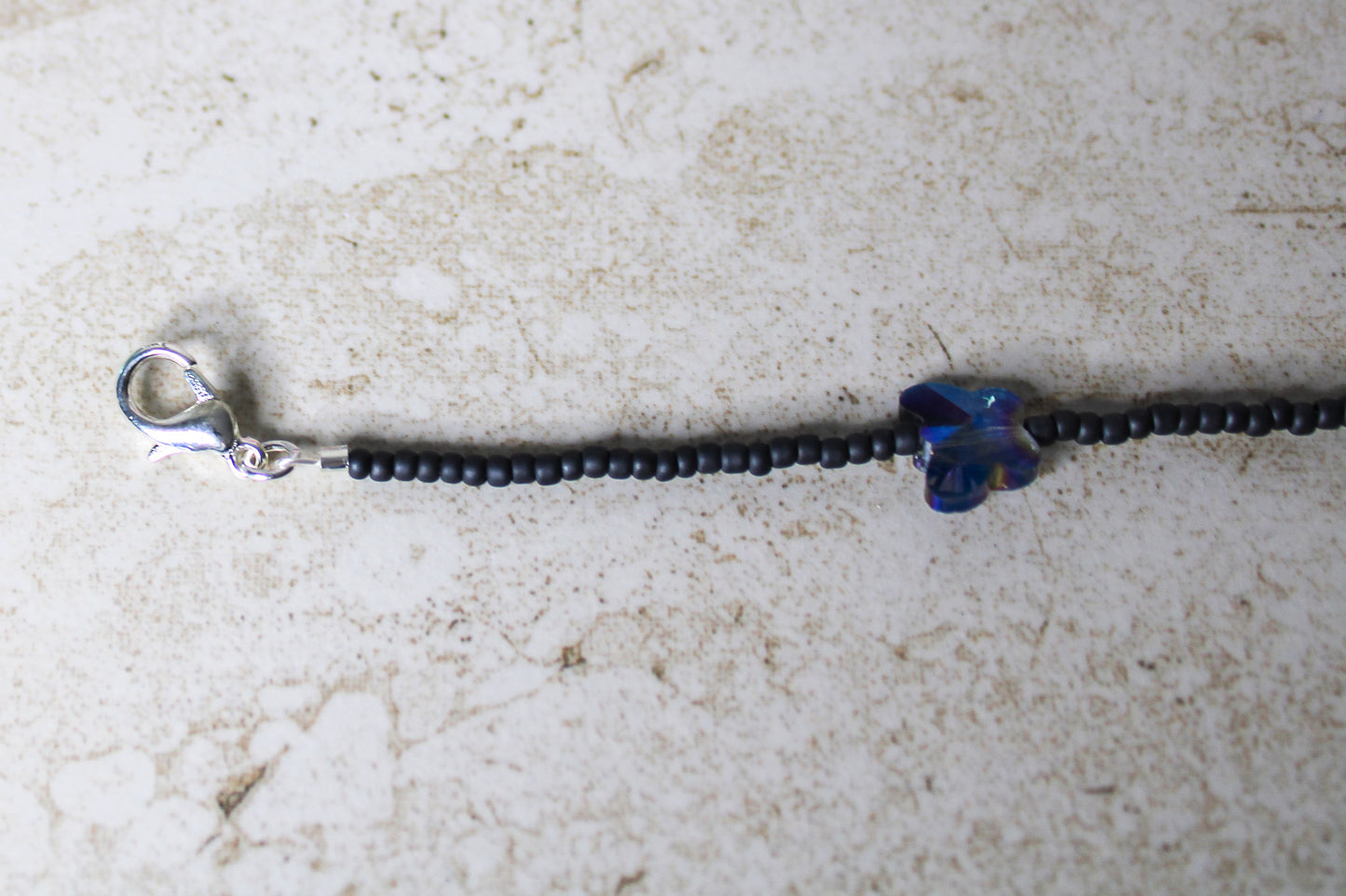 Close-up of the lobster clasp, highlighting the strong and secure closure of the grey and blue butterfly necklace.