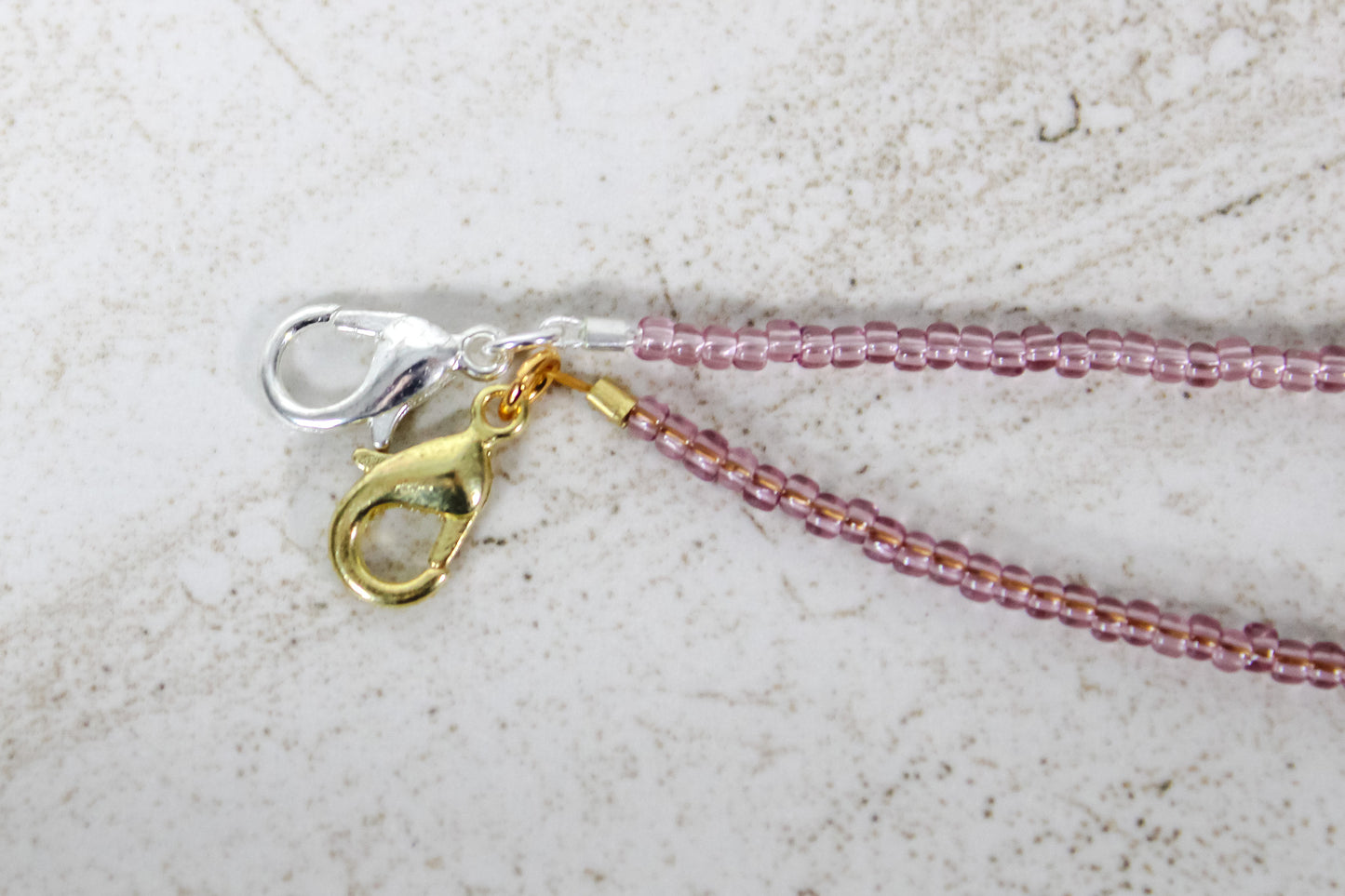 A close up of the gold and silver lobster clasps on a garnet bracelet.