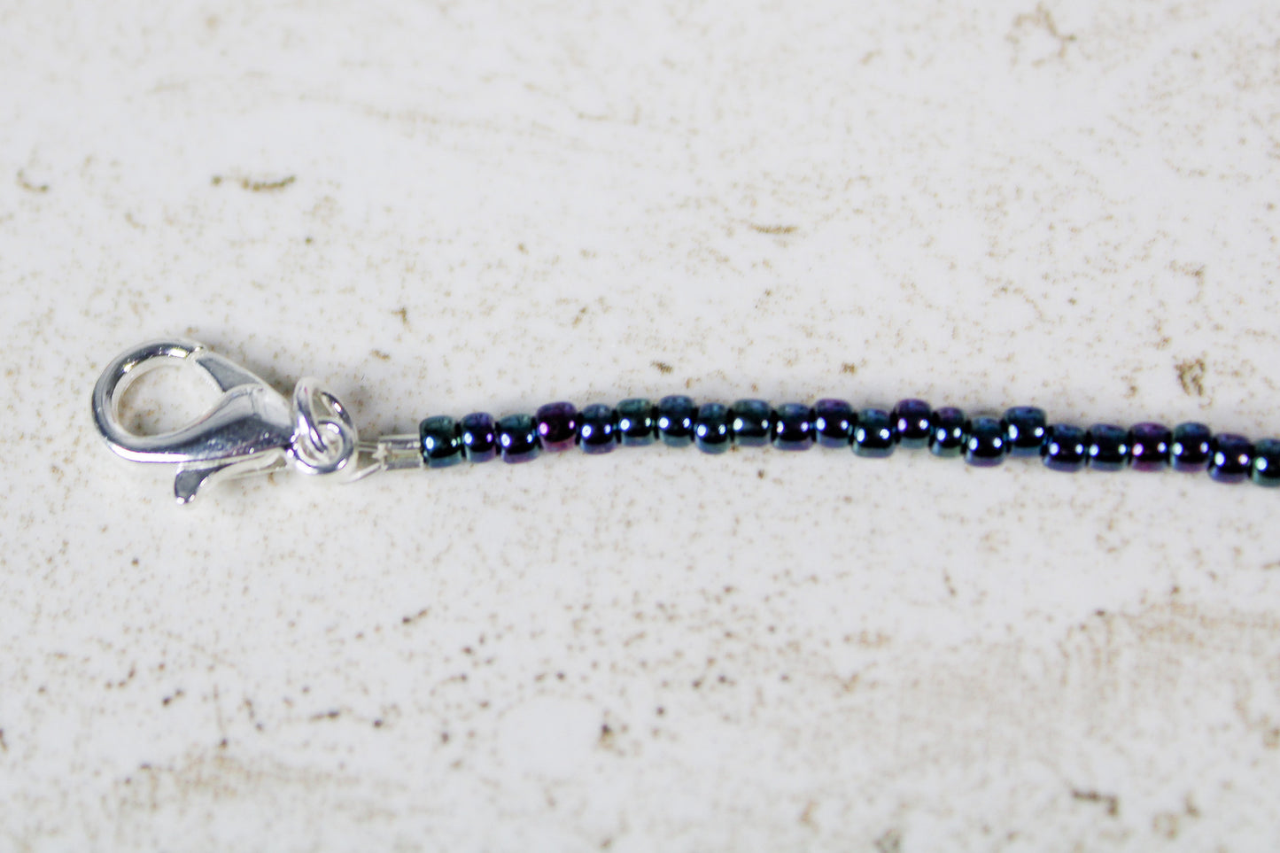 Zoomed-in image of the silver lobster claw clasp attached to the end of the beaded Just Dance bracelet.