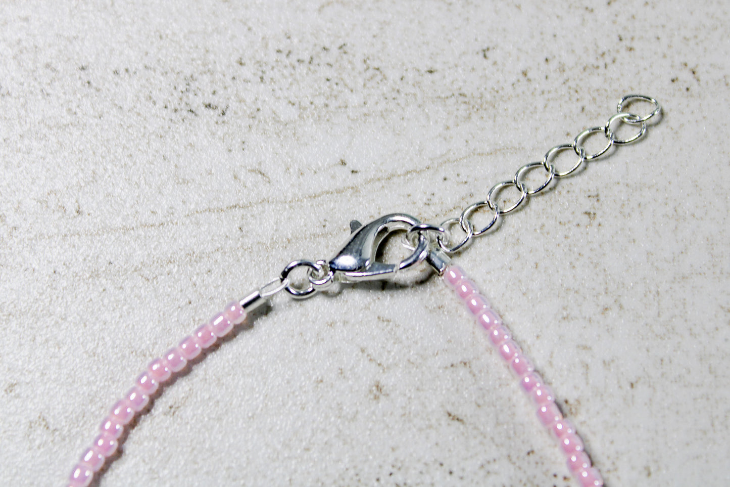 Zoomed view of light pink beads and centered white letter beads.