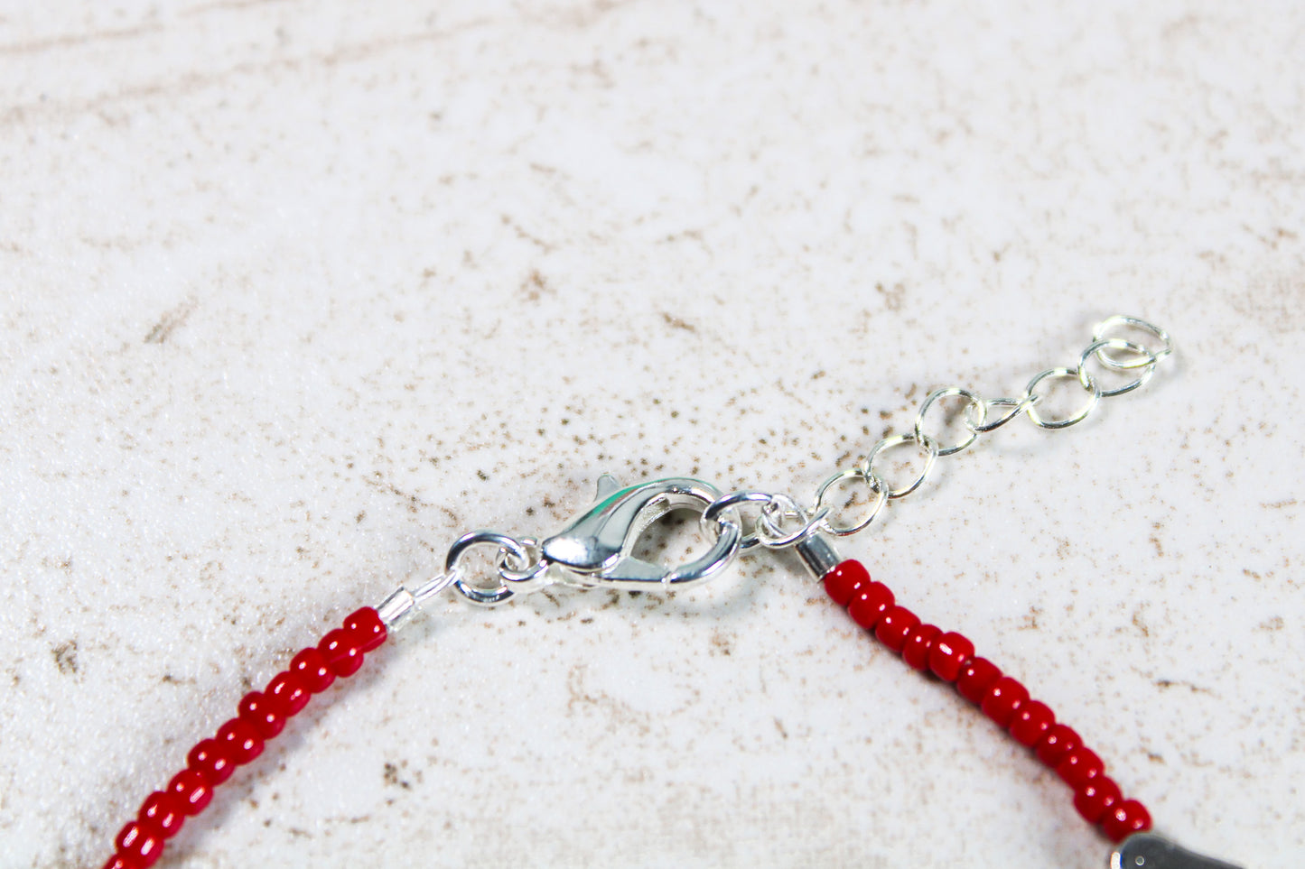 A close up of the bracelet closure featuring the silver lobster claw clasp attached to the silver extender chain.