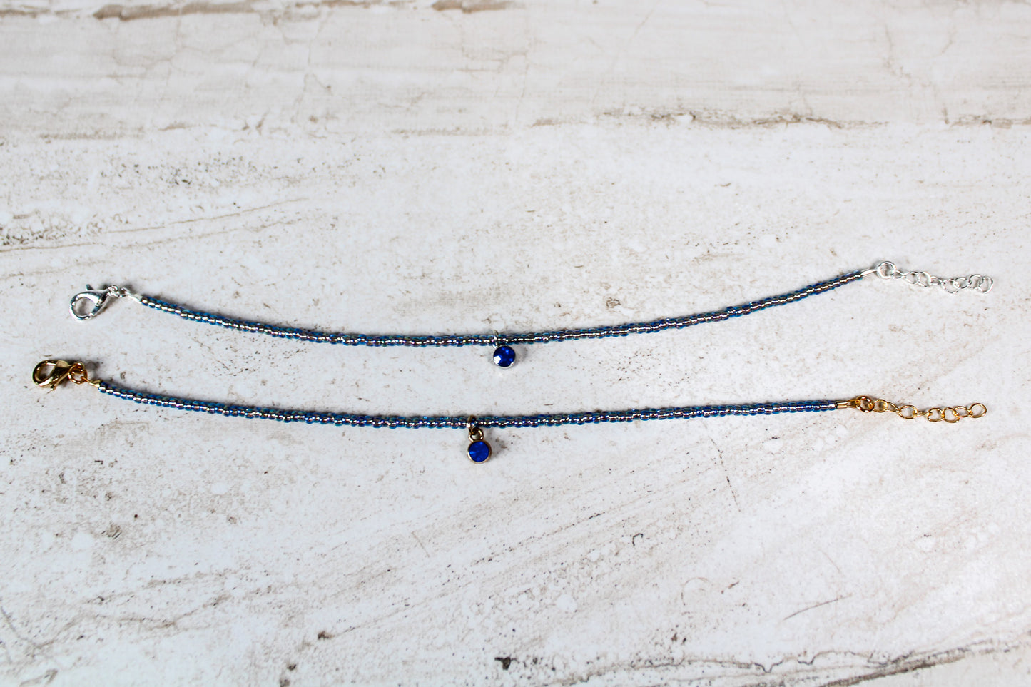 Gold and silver versions of the sapphire-inspired September bracelet side by side, showing contrast in tone and hardware.