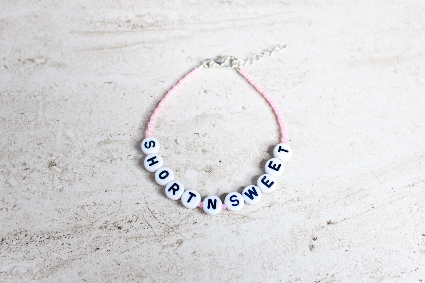 Handmade Short n Sweet bracelet with light pink seed beads and silver finishes shown in a flat lay overview