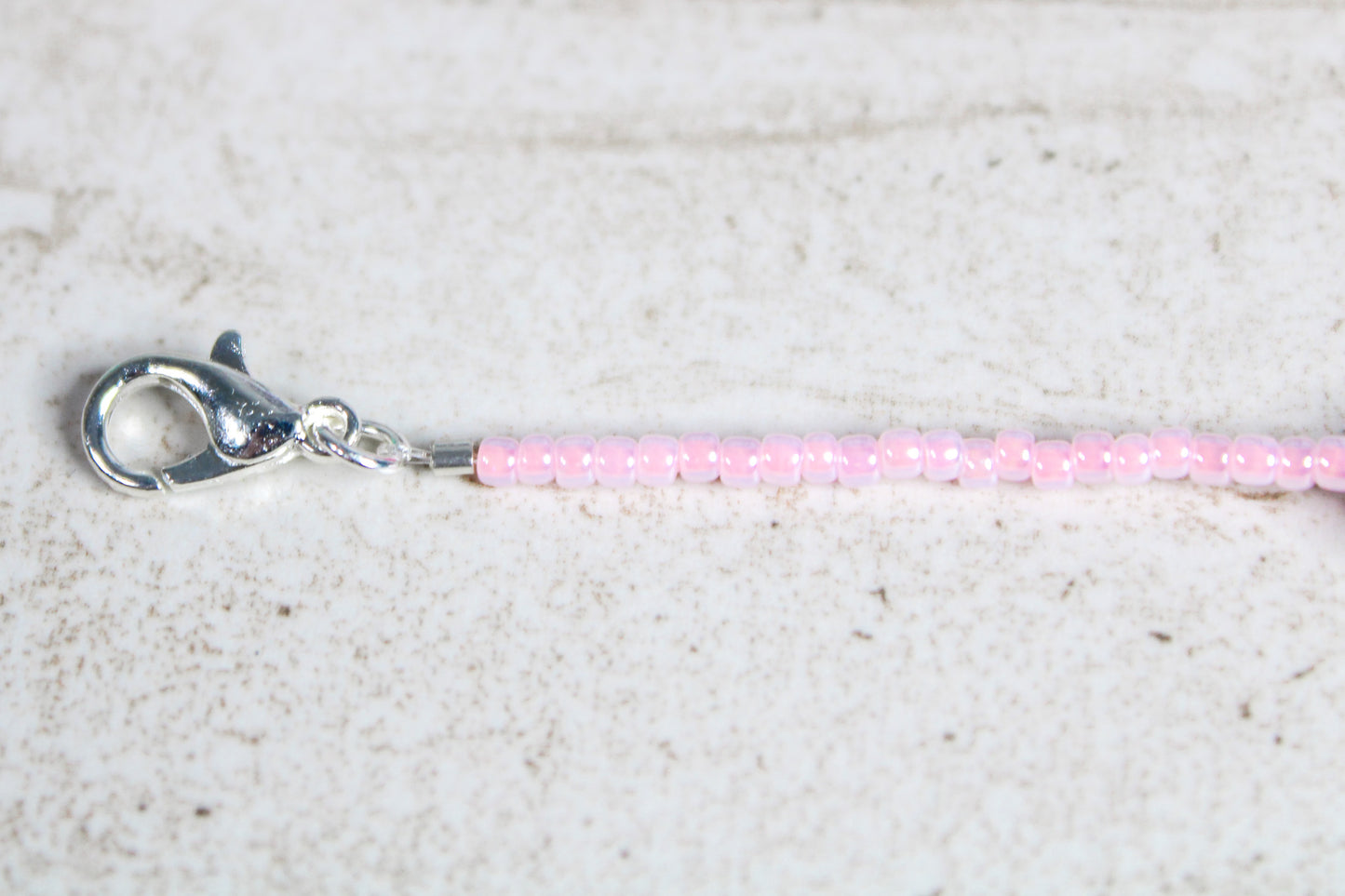 Zoomed-in view of the silver lobster claw clasp at the end of the light pink beaded bracelet