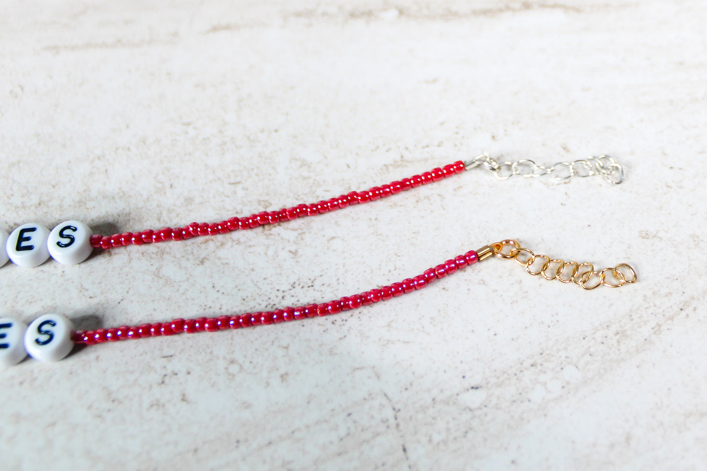 A close up of the gold and silver extender chains on a shiny red bracelet.