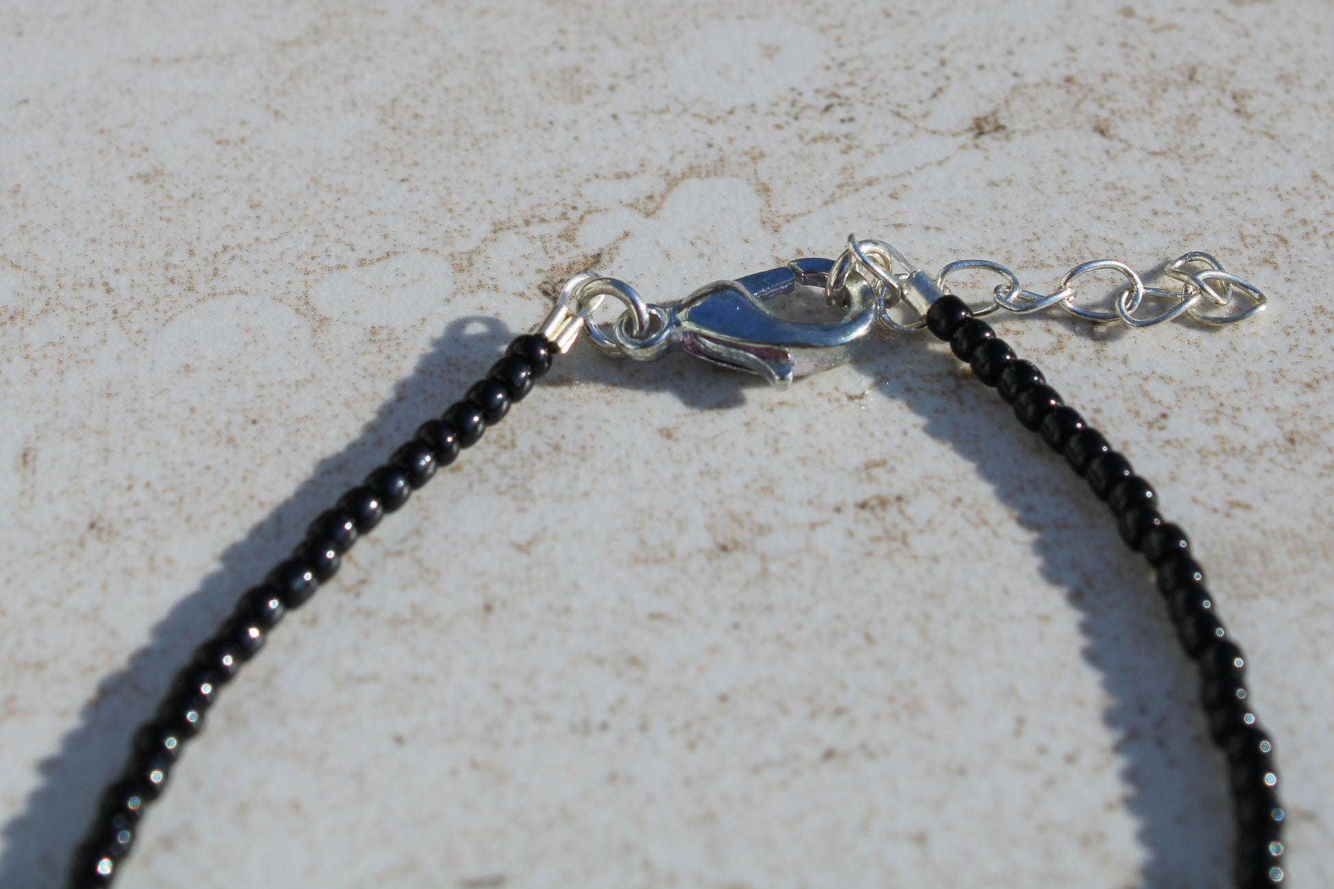 A close up of the bracelet closure featuring the silver lobster claw clasp attached to the silver extender chain.