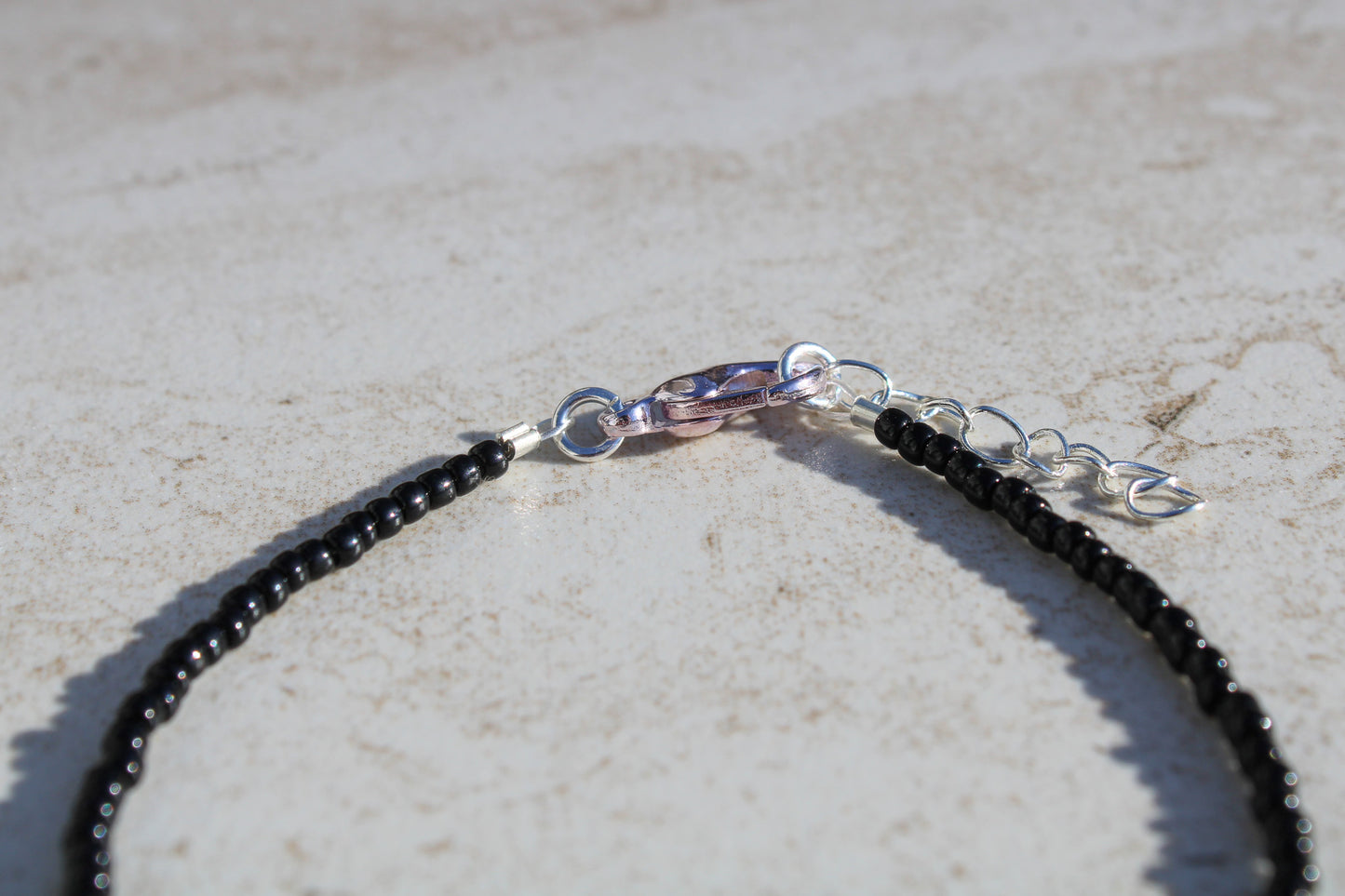 A close up of the bracelet closure featuring the silver lobster claw clasp attached to the silver extender chain.