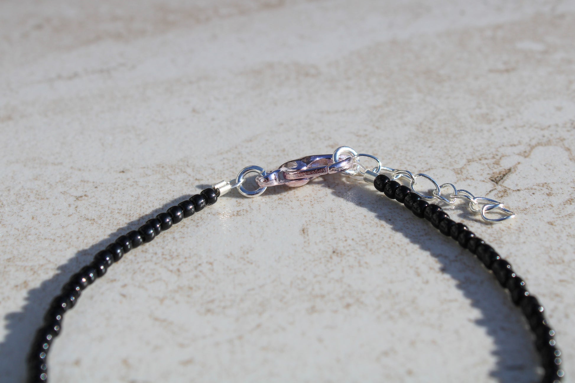 A close up of the bracelet closure featuring the silver lobster claw clasp attached to the silver extender chain.