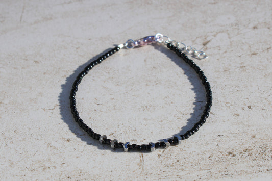 A bracelet made out of black seed beads and 6 small silver arrow charms.  Features a silver lobster claw clasp and chain extender.