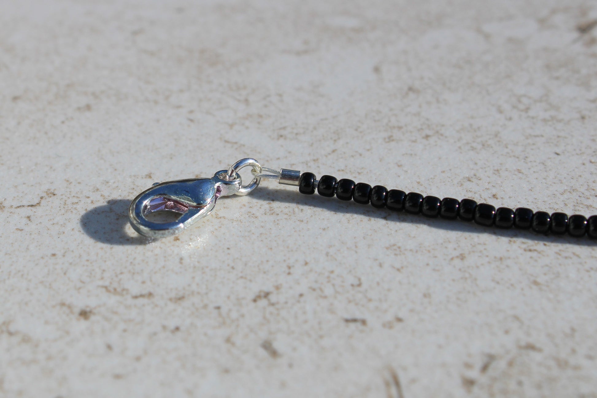 A close up of the silver lobster claw clasp at the end of the bracelet.