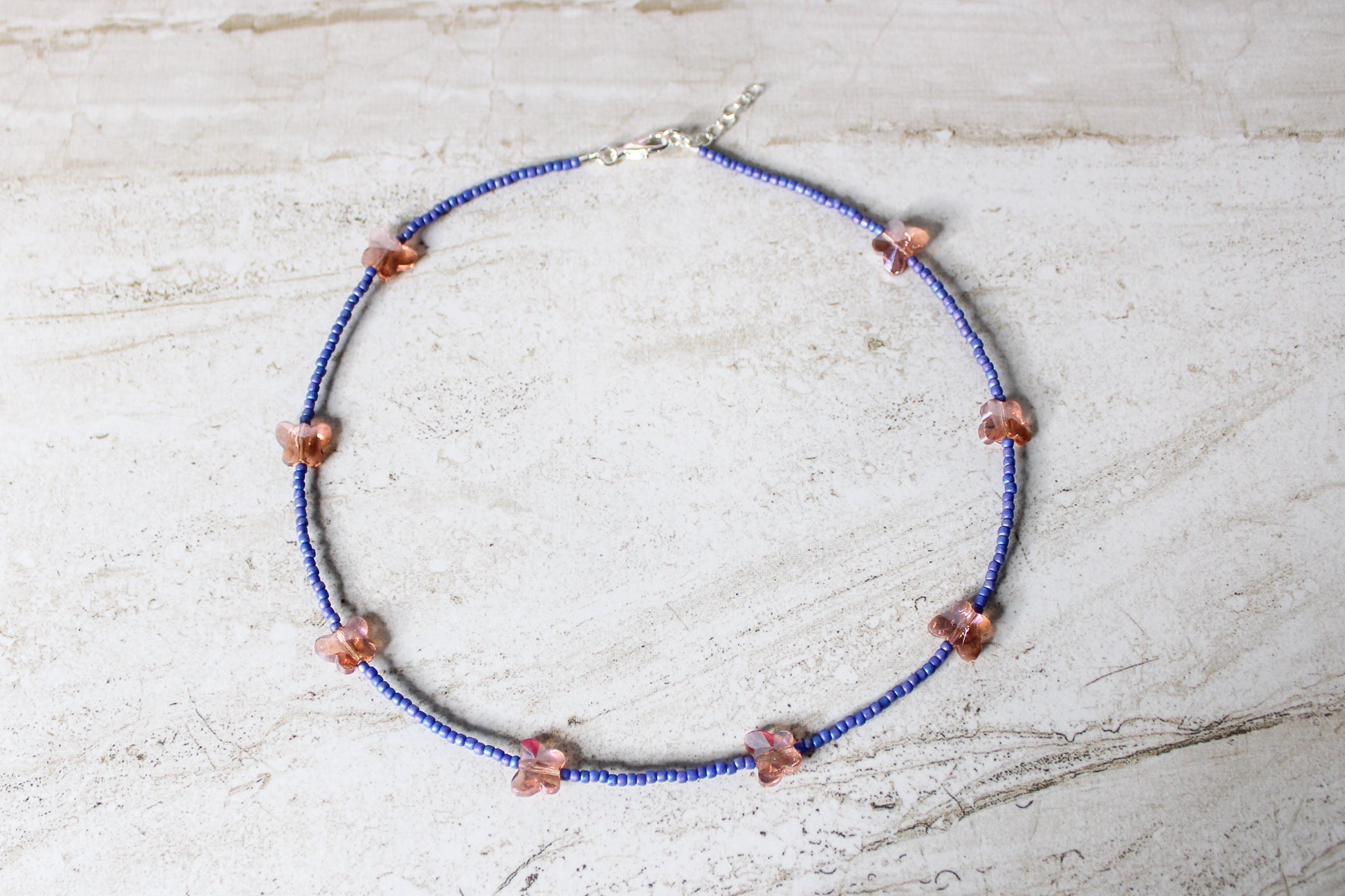 A bold and playful blue and orange butterfly necklace featuring vibrant glass beads and a whimsical butterfly charm.