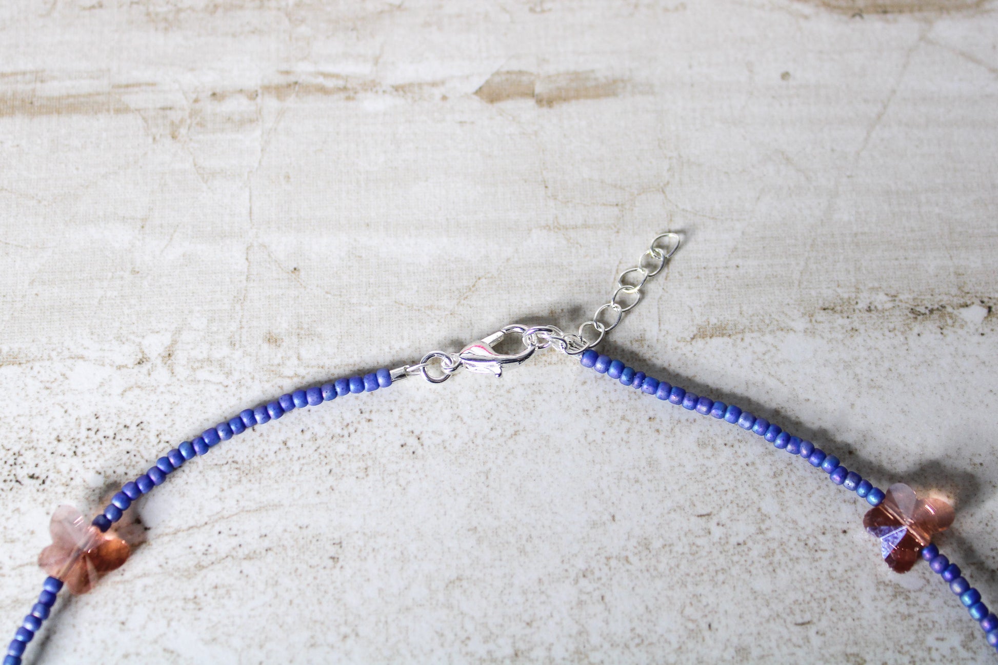 A bold and playful blue and orange butterfly necklace featuring vibrant glass beads and a whimsical butterfly charm.