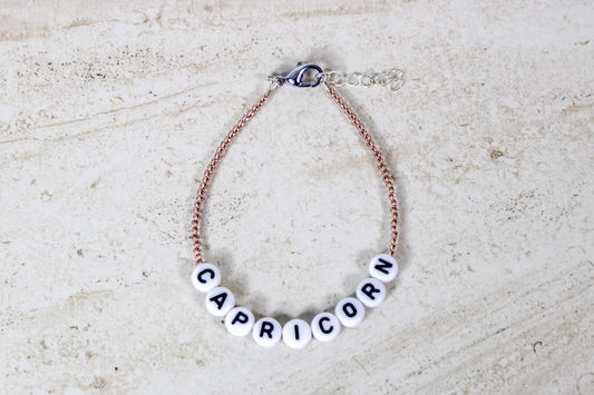 A copper colored seed bead bracelet with Capricorn in round letter beads and silver lobster clasp and extender chain.
