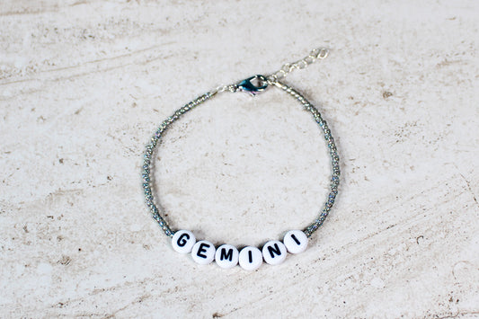 Dainty Gemini bracelet with shimmering twin-tone beads and a silver lobster clasp, styled on a white background.