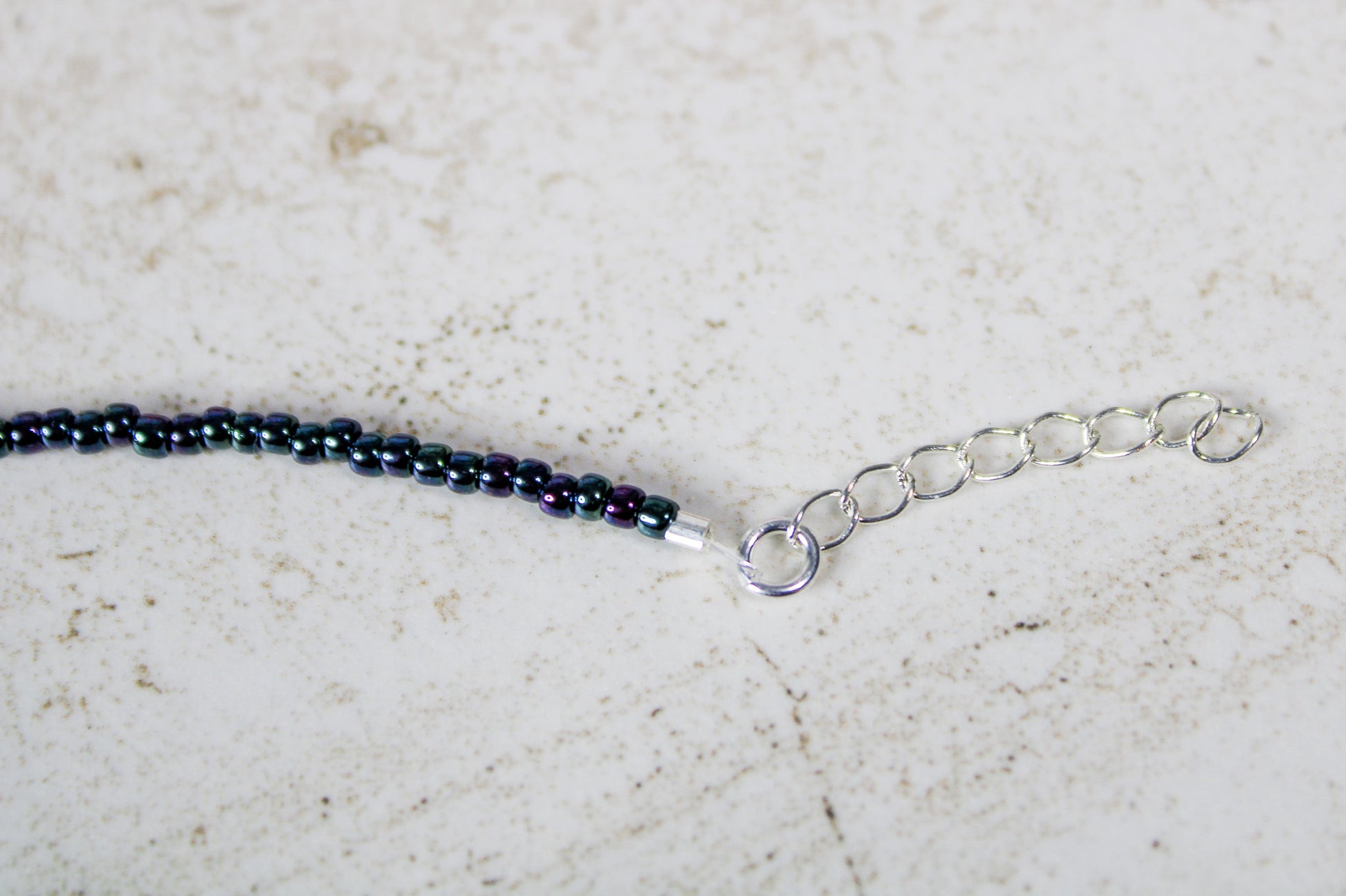 Close-up of the silver extender chain showing the adjustable length of the Just Dance seed bead bracelet.