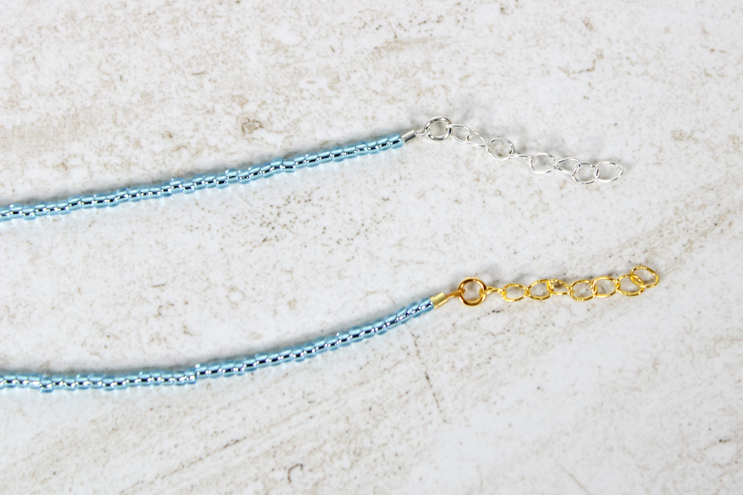 A close up of the gold and silver extender chains on an aquamarine bracelet.