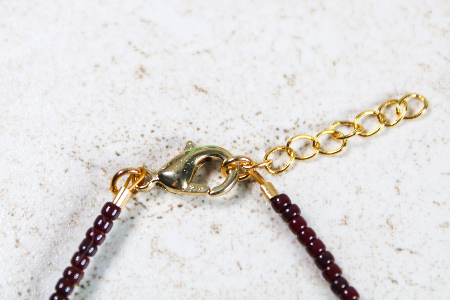 A close up of the bracelet closure featuring the gold lobster claw clasp attached to the gold extender chain.