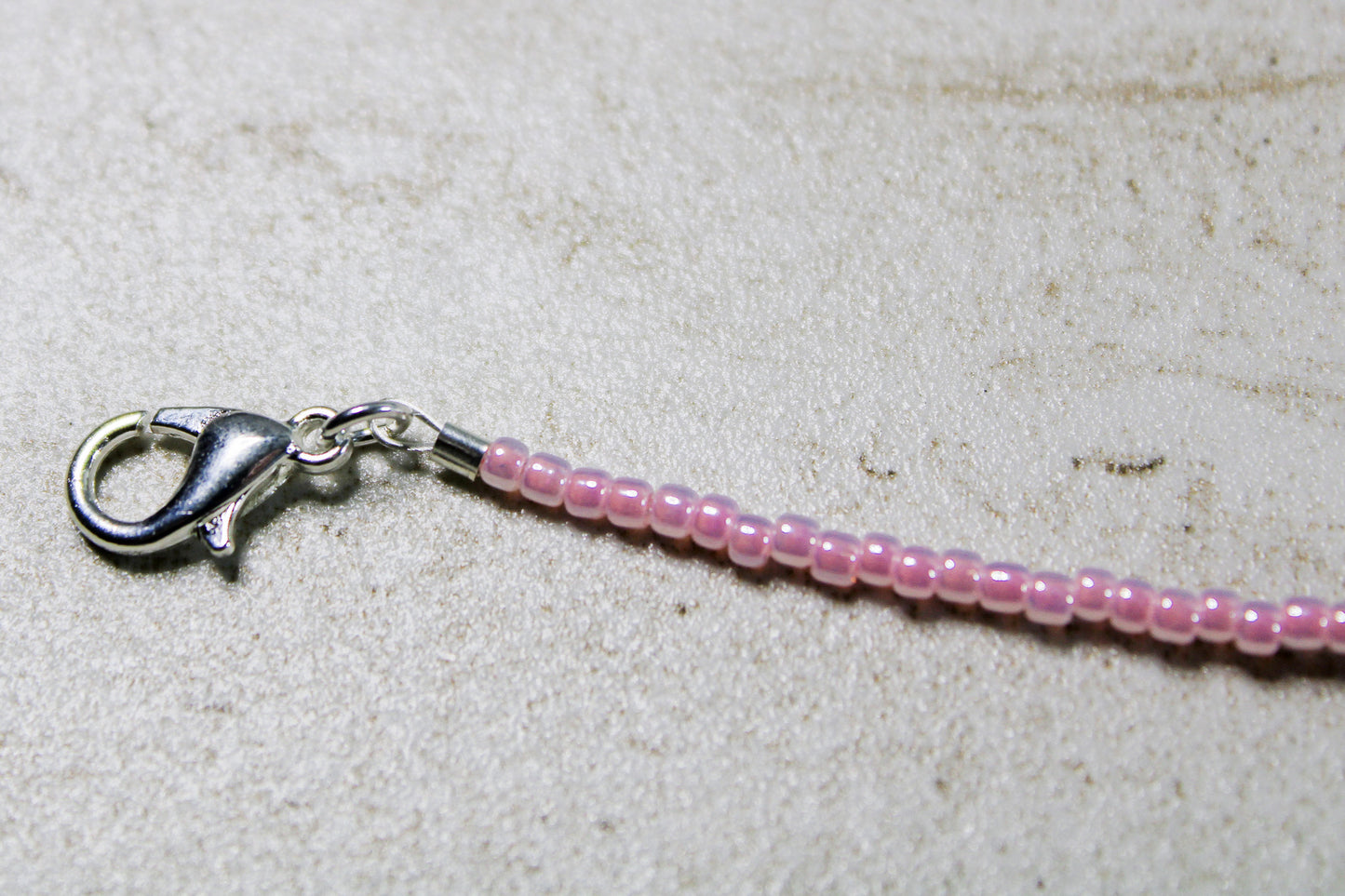 Silver lobster clasp detail next to beadwork.