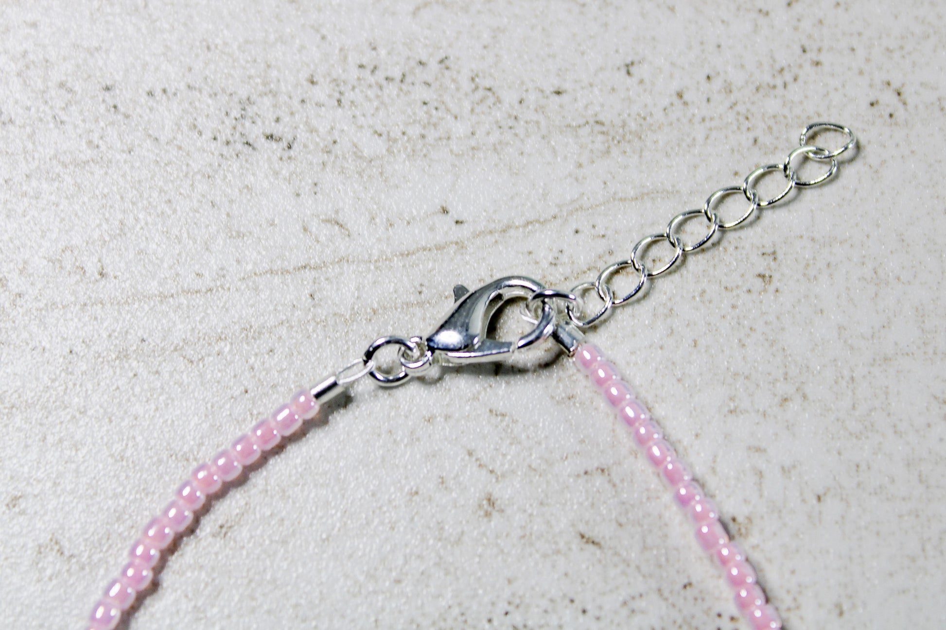 Zoomed view of light pink beads and centered white letter beads.