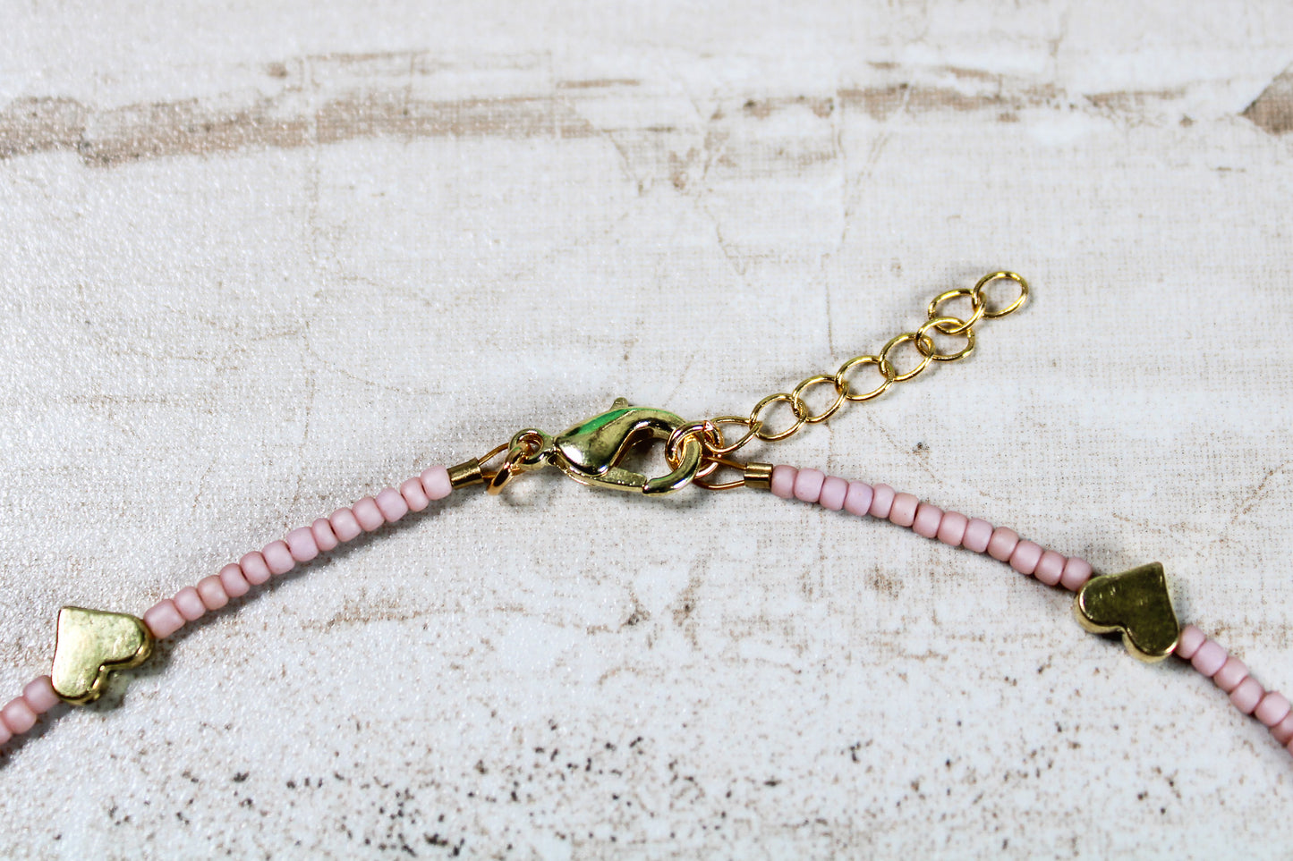 A close up of the necklace closure featuring the gold lobster claw clasp attached to the gold extender chain.