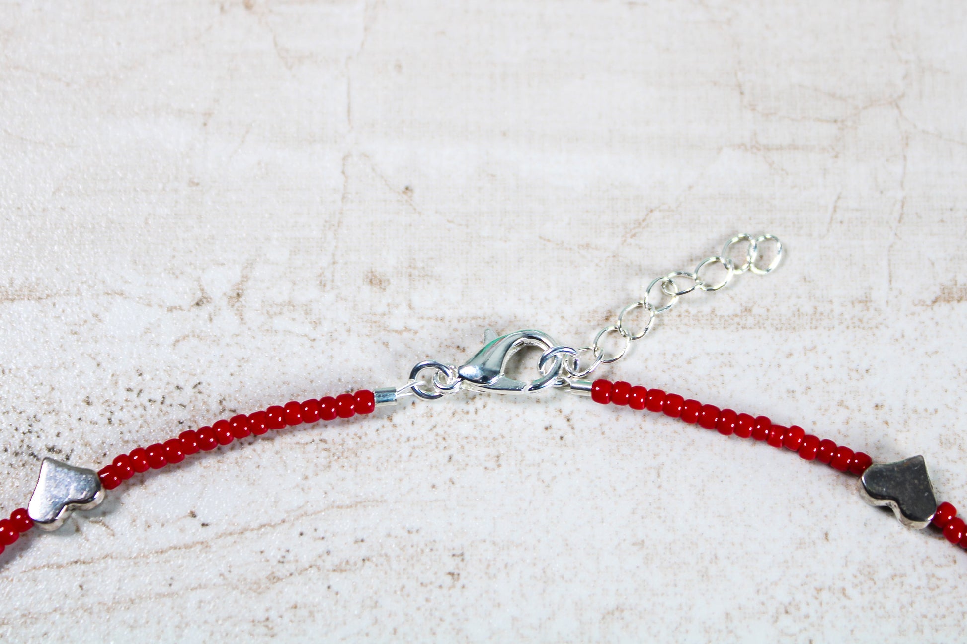 A close up of the necklace closure featuring the silver lobster claw clasp attached to the silver extender chain.