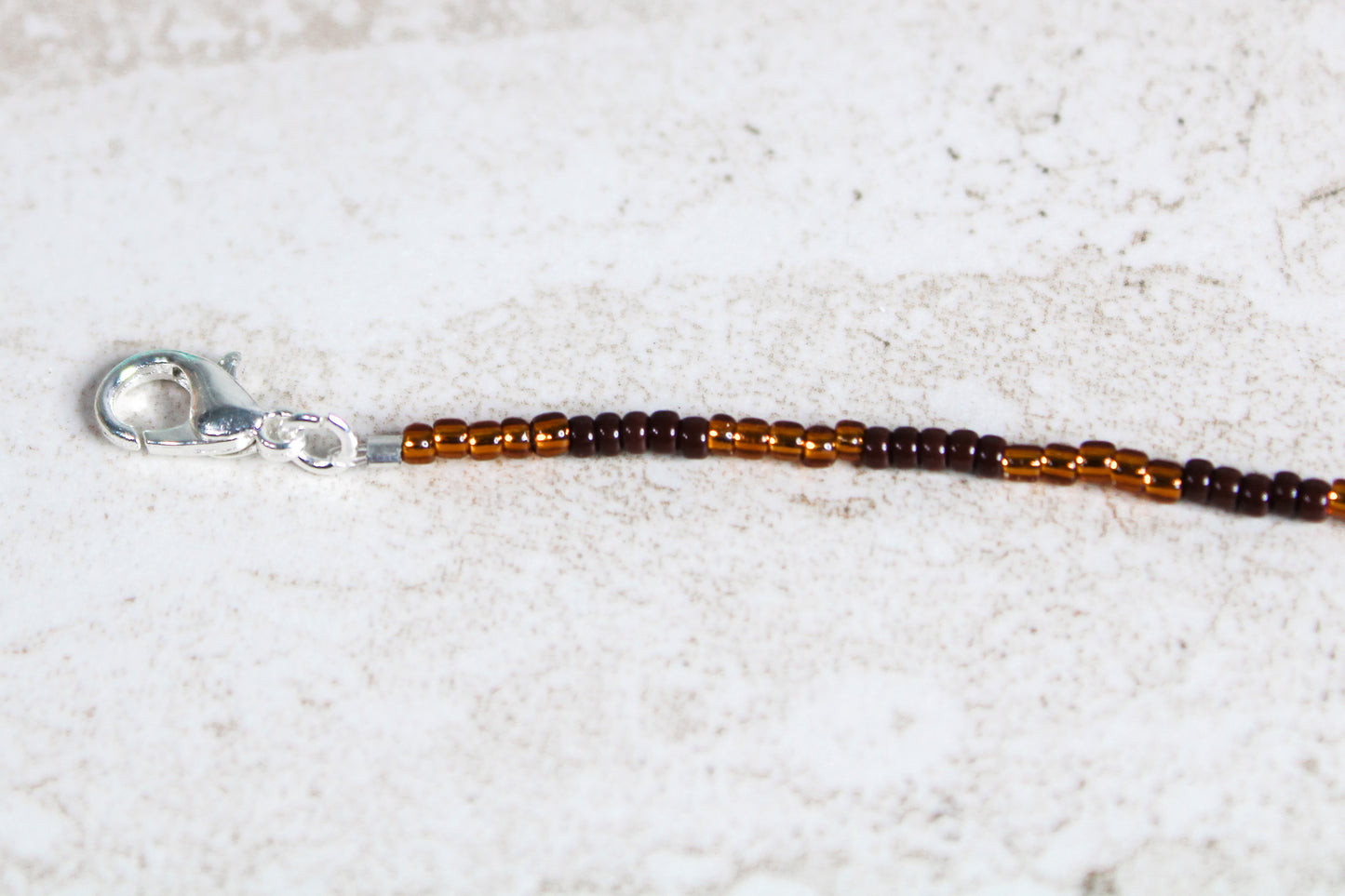 Silver lobster clasp attached to the end of the seed bead strand, connected securely with jump rings.