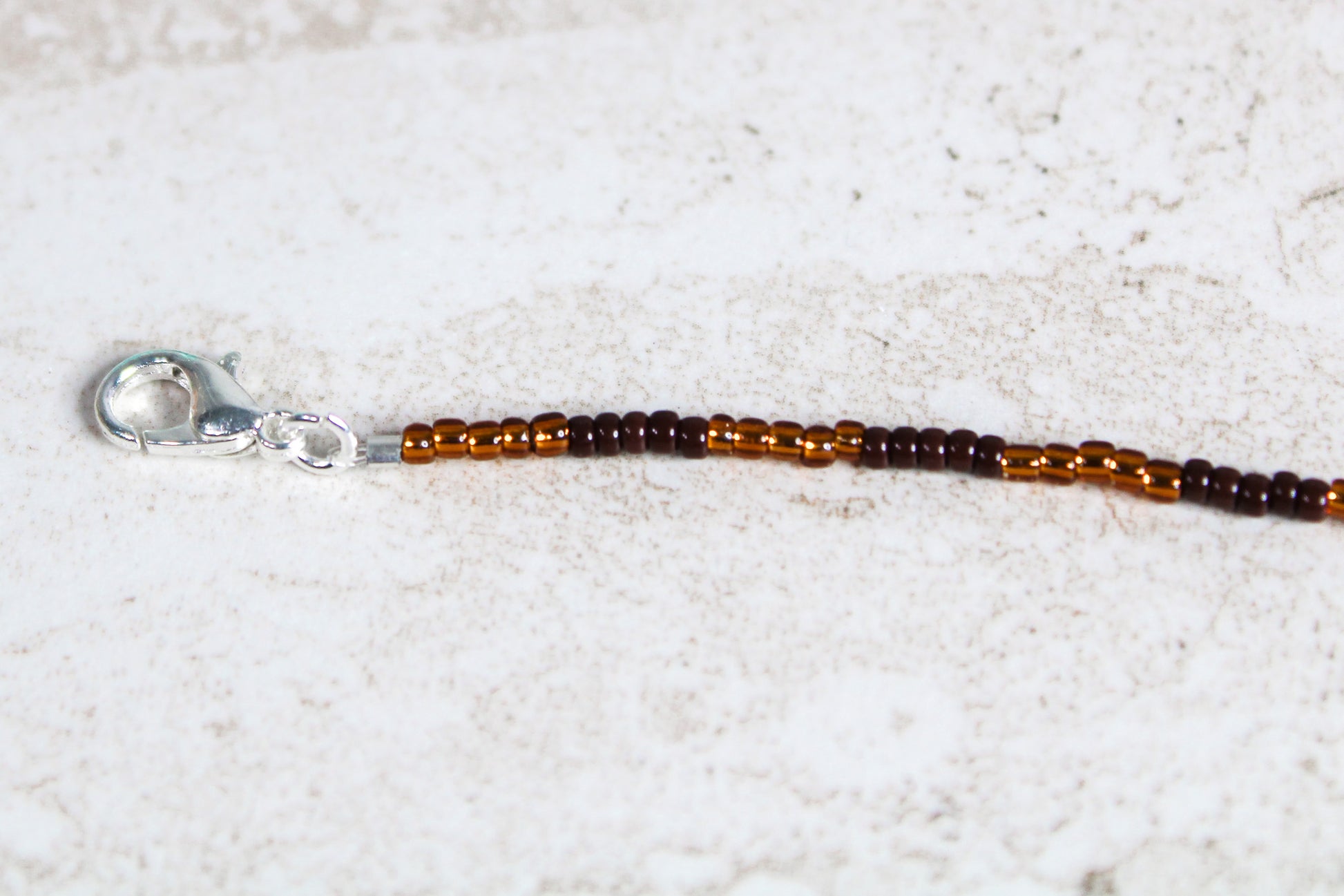 Silver lobster clasp attached to the end of the seed bead strand, connected securely with jump rings.